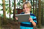 Boy using digital tablet in forest