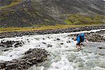 Hiker crossing mountain river