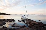 Sailing boat moored at rocky coast