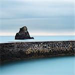 Stone wall and rock at sea