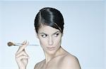 Woman holding make-up brush, looking away