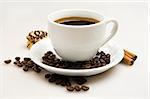 Cup of coffee with beans and cinnamon sticks over white background