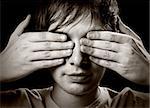 Portrait of a young man covering his eyes with hands