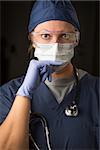 Concerned Female Doctor or Nurse Wearing Protective Facial Wear and Surgical Gloves.