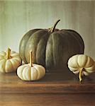 Green pumpkin and small white gourds on table