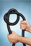 Man holding a flexible plastic hose with a knot.