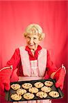 Sweet old fashioned grandma holding a tray of her homemade cookies.  Room for text.