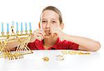 Little boy playing driedel and eating gelt on Hanukkah.  White background.