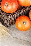 Ripe small pumpkins in basket on wooden table background