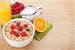Healty breakfast with muesli, berries, milk and orange juice on wooden table with copy space