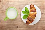 Milk and fresh croissant on wooden table