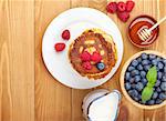 Pancakes with raspberry, blueberry, milk and honey syrup. On wooden table with copy space