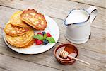 Pancakes with raspberry, blueberry, milk and honey syrup. On wooden table