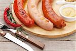 Various grilled sausages with condiments on cutting board