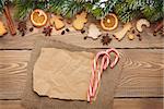 Christmas wooden background with snow fir tree, spices, gingerbread cookies and paper for copy space