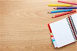 Office table with blank notepad and colorful pencils. View from above with copy space