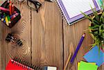 Office table with notepad, colorful pencils, supplies and flower. View from above with copy space