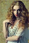 lovely sensual woman wearing antique clothes and jewellery and posing with long curly hair. fashion vintage portrait