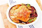 Luxurious golden baked chicken in white oval baking dish prepared for eating. Top view.