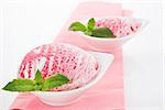 Tasty cherry ice cream in white bowl decorated with mit leaf. Summer food styling.