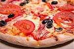 Delicious Italian pizza with ham, tomatoes and olives, selective focus