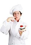 Pretty pastry cook in chef's whites tasting a delicious chocolate cheesecake tart with whipped cream and a cherry on top.  Isolated on white background.