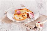 Baguette with garlic on white plate on white wooden textured background. Luxurious food background.