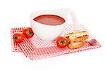 Tomato soup in white bowl with fresh tomatoes and garlic bread on red and white dotted napkin. Culinary soup eating, minimal modern style.