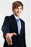 Young businessman giving a hand shake, over a gray background