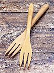 Two Small Wooden Forks isolated on Textured Wooden background. Focus on Foreground