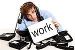 Exhausted man full of work, sitting with a bunch of phones over him and holding a cardboard with the word Work.