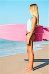 A beautiful surfer girl looking at the beach with her surfboard