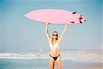 A beautiful surfer girl at the beach with her surfboard