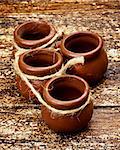 Four Small Empty Handmade Pottery Pots with Rope closeup on Textured Wooden background