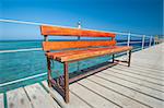 Wooden bench seat on jetty at tropical beach resort