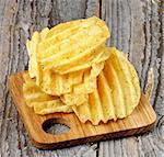 Stack of Rifled Crispy Potato Chips on Wooden Plate closeup on Rustic Wooden background