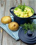 Delicious Homemade Mashed Potato with Dill and Spring Onion in Dark Blue Casserole with Lid on Rustic Wooden background