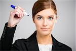 Beautiful businesswoman holding a pen and making a sketch on a glass board with a marker