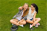 Female best friends sitting on the grass and having a good time