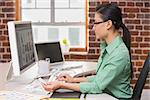 Side view of concentrated female photo editor using computer in the office