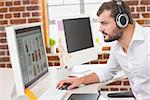 Side view of concentrated male photo editor using computer in the office