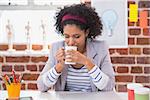 Female interior designer drinking coffee at office desk