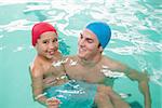 Cute little boy learning to swim with coach at the leisure center