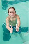 Little boy showing thumbs up in the pool at the leisure center