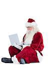 Santa sits and uses a laptop on white background