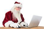 Santa surfs on the internet at a desk on white background