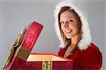 Festive pretty brunette opening a gift on gray background