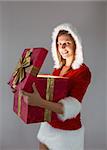 Smiling girl opening a gift and looking at the camera on gray background