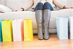 Woman sitting on couch with shopping bags at home in the living room