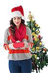 Festive brunette holding gift by the tree on white background